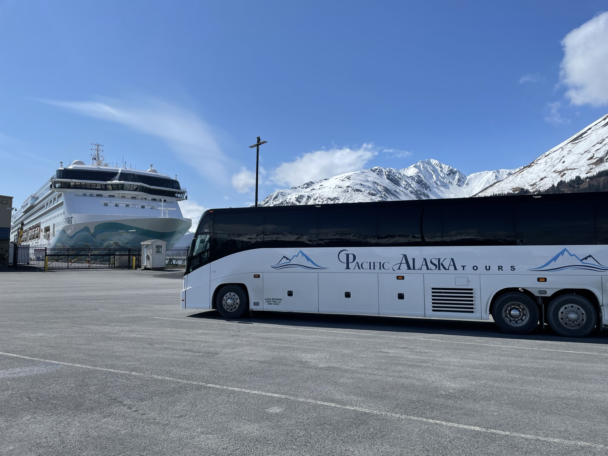 Motorcoach with mountains and cruise ship in background